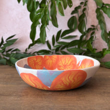 Load image into Gallery viewer, Bowl with orange and yellow, and blue and purple flower patterns, on a wood table with greenery in background