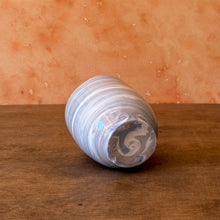 Load image into Gallery viewer, Vase with a swirled gray and blue pattern laying on its side to show the bottom on a wooden surface