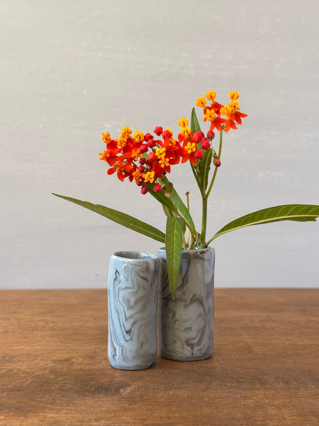 Two small gray vases with floral arrangement on a wooden surface