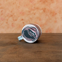 Load image into Gallery viewer, Bottom of mug with marble patterned  on a wooden surface 
