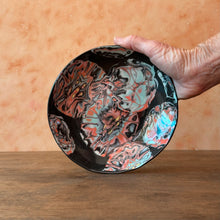 Load image into Gallery viewer, Hand holding a marbled ceramic plate with a colorful design on a wooden surface.
