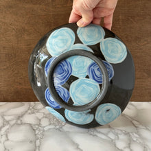 Load image into Gallery viewer, Bottom of a black bowl with blue circular patterns on a marble surface
