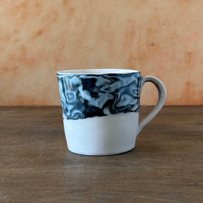 Marbled ceramic mug on a wooden surface with a wooden background