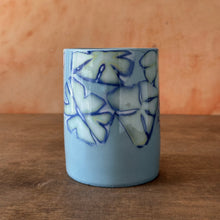 Load image into Gallery viewer, Blue porcelain vessel with floral patterns on a wooden surface
