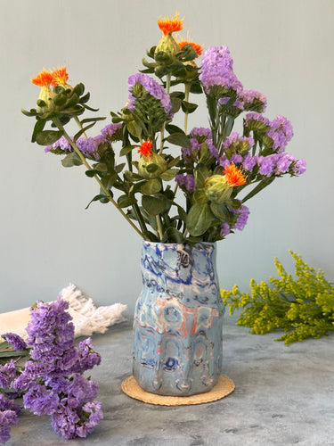 Decorative vase with colorful floral arrangement on a light gray background