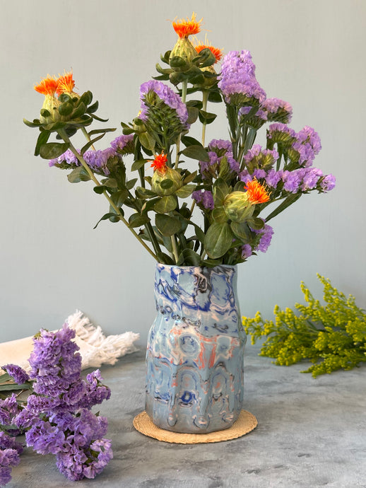 Decorative vase with colorful floral arrangement on a light gray background