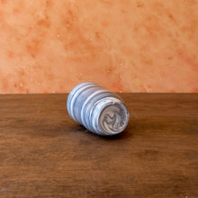 Load image into Gallery viewer, Marbled vase laying on its side showing the bottom on a wooden surface 
