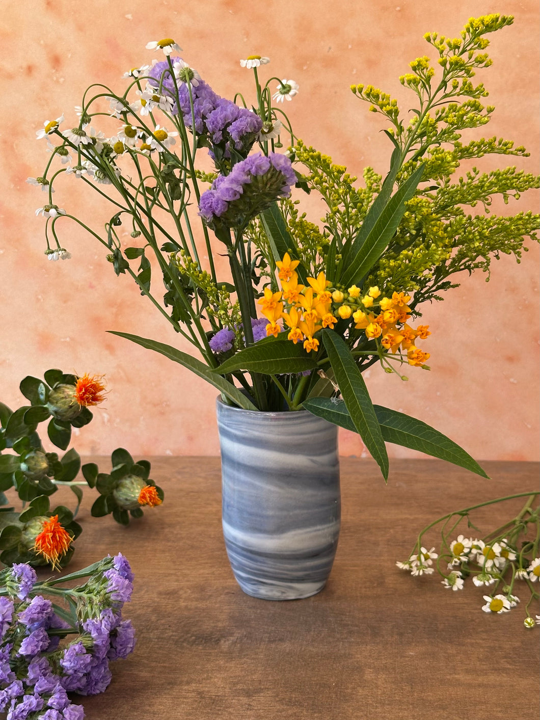 Bouquet of flowers in a gray and white vase on a wooden surface 
