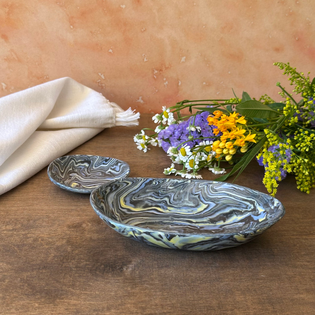 Marbled ceramic bowl and smaller dish on a wooden surface with flowers and a cloth.