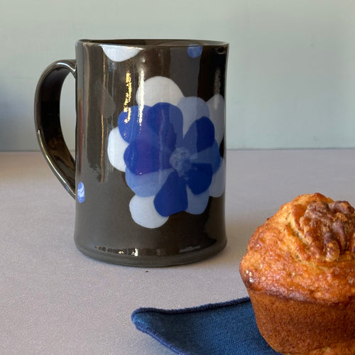 Black mug with blue flower and muffin