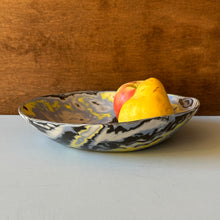 Load image into Gallery viewer, Decorative ceramic bowl with blue, yellow, and black pattern containing a pear on a wooden surface
