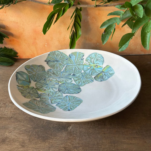 Ceramic plate with leaf pattern on a wooden surface