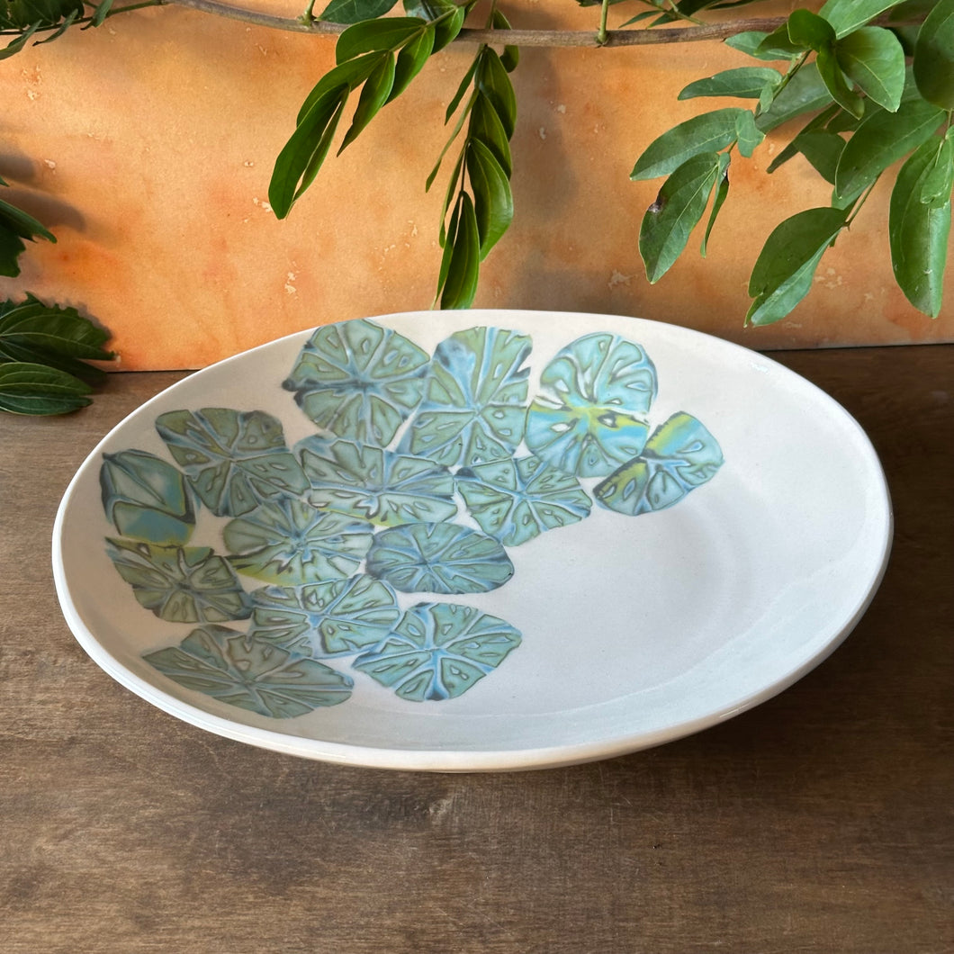 Ceramic plate with leaf pattern on a wooden surface