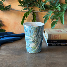 Load image into Gallery viewer, Marbled ceramic cup on a wooden surface with books and plants in the background
