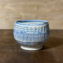 Load image into Gallery viewer, A handmade ceramic bowl with blue and white patterns, sitting on a dark wooden surface against a light wood background.
