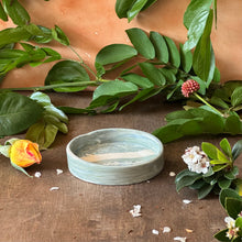 Load image into Gallery viewer, Ceramic wine bottle coaster on a wooden surface with green leaves and flowers
